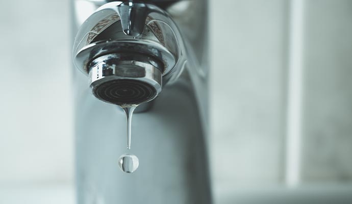 leaky faucet water drop dripping from the tap and water shortage